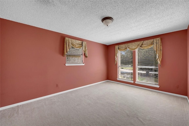 carpeted empty room featuring baseboards and a textured ceiling