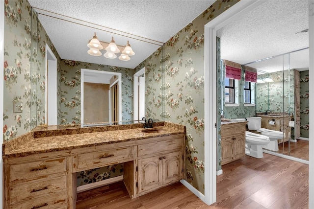 bathroom featuring a textured ceiling, toilet, and wallpapered walls