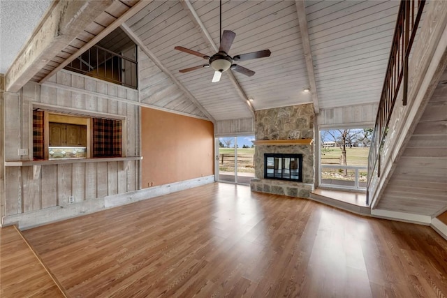 unfurnished living room with a fireplace, wood finished floors, and beam ceiling