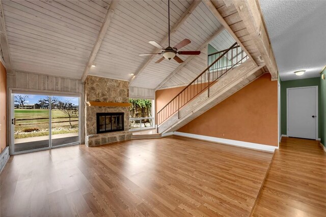 unfurnished living room with a fireplace, baseboards, beamed ceiling, and wood finished floors