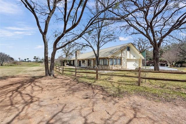 view of front facade featuring a garage, stone siding, and fence