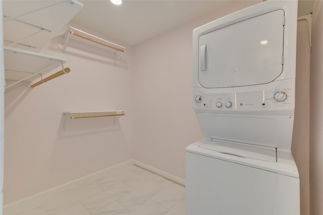 laundry room featuring laundry area, baseboards, marble finish floor, and stacked washer / drying machine