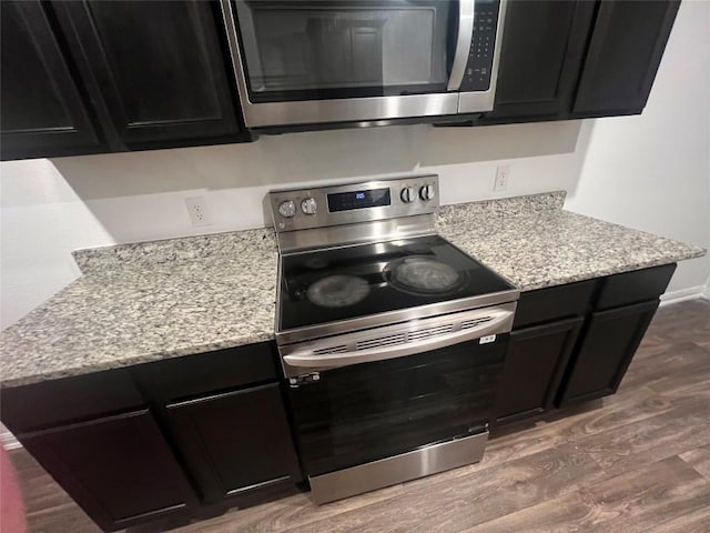 14009 John Aregood Pass, Elgin, TX 78621 - kitchen featuring appliances with stainless steel finishes, dark cabinetry, wood finished floors, and light stone counters