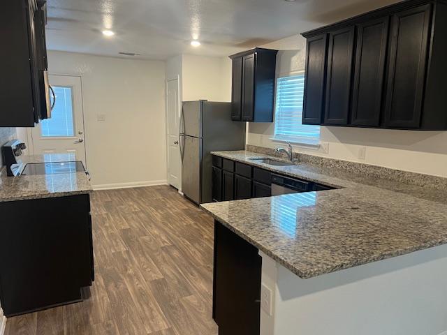 14009 John Aregood Pass, Elgin, TX 78621 - kitchen with dark cabinets, light stone counters, freestanding refrigerator, range, and dark wood-style floors