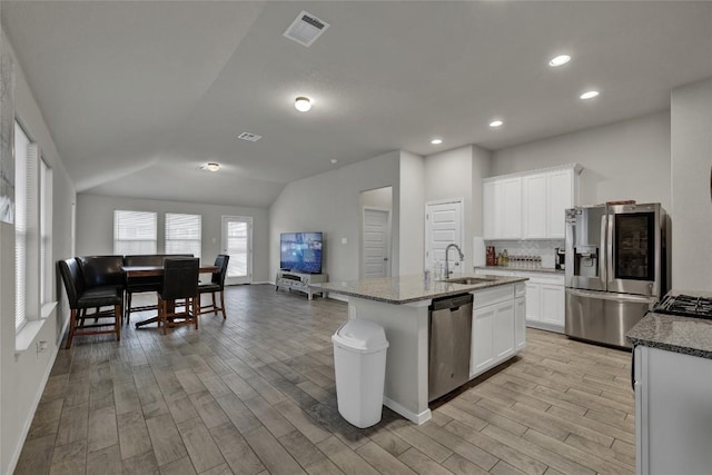 kitchen featuring stainless steel appliances, lofted ceiling, visible vents, a sink, and light wood-type flooring