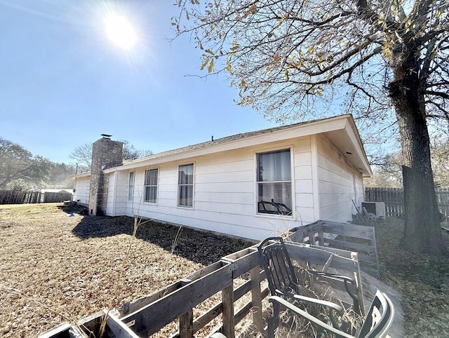 view of side of home with a chimney and fence