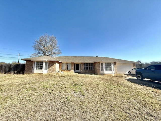 single story home with a garage, brick siding, a front yard, and fence