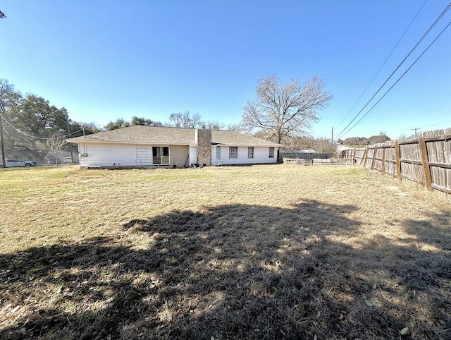 back of house featuring a yard and fence