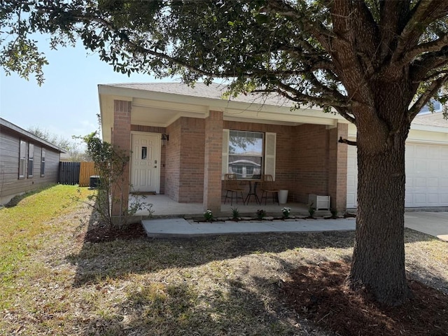 view of front of home featuring a porch, an attached garage, fence, and brick siding