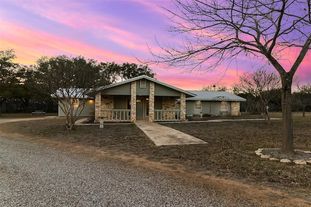 view of front of house with stone siding, covered porch, and driveway