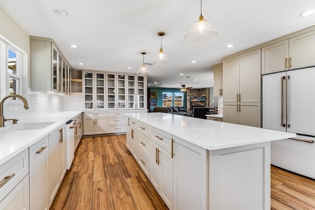 kitchen with light wood finished floors, white dishwasher, a sink, and a center island