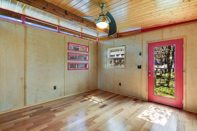 unfurnished room featuring wooden ceiling, beamed ceiling, wood finished floors, and a healthy amount of sunlight