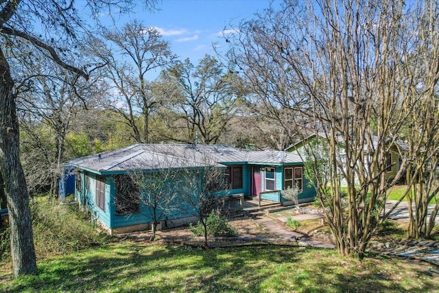 view of front of property with metal roof, driveway, and a front yard