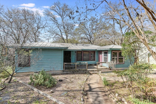 ranch-style house featuring covered porch and metal roof