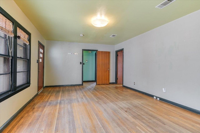 spare room featuring wood finished floors, visible vents, and baseboards