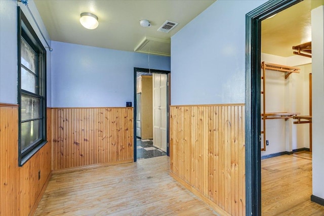 hall with visible vents, wainscoting, attic access, and wooden walls