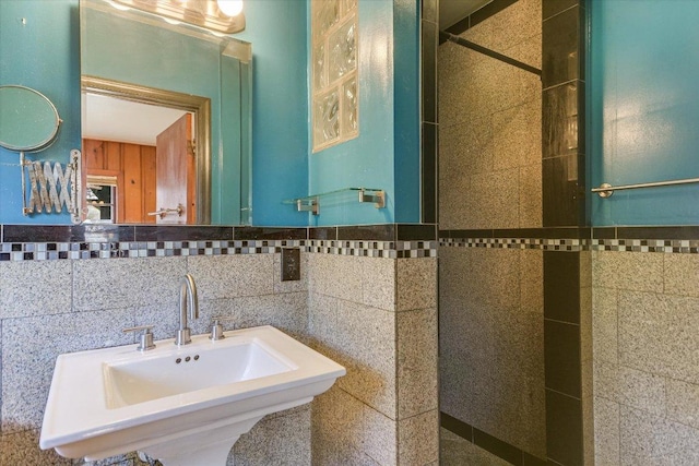 full bath featuring a tile shower, tile walls, and a sink