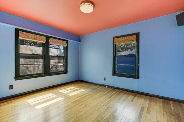 unfurnished room featuring baseboards and hardwood / wood-style floors