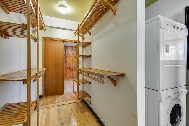 clothes washing area featuring laundry area, stacked washer and dryer, and light wood-style floors