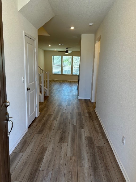 hallway with baseboards, dark wood finished floors, and stairs