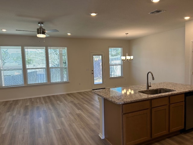 kitchen with visible vents, a sink, stainless steel dishwasher, wood finished floors, and hanging light fixtures