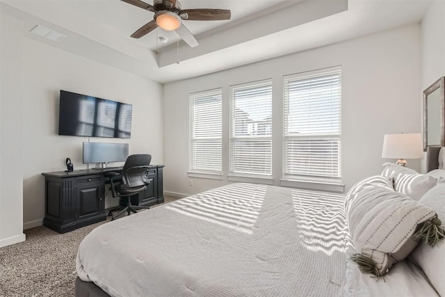 carpeted bedroom with a ceiling fan, a raised ceiling, visible vents, and baseboards