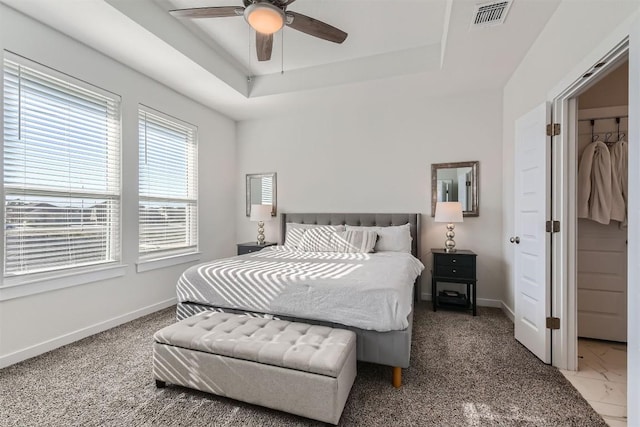 bedroom featuring ceiling fan, a raised ceiling, visible vents, and baseboards