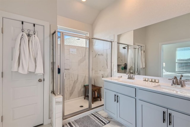 bathroom featuring lofted ceiling, a stall shower, double vanity, and a sink