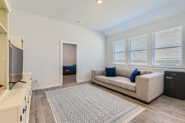 living room featuring wood finish floors, lofted ceiling, and baseboards