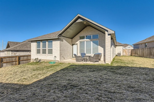 back of property with brick siding, a patio, a lawn, central AC, and a fenced backyard