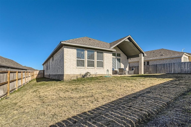 back of house featuring a patio area, a fenced backyard, a yard, and brick siding