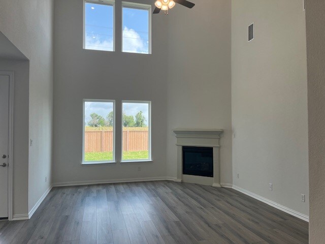 513 Teasley Dr, Taylor, TX 76574 - unfurnished living room featuring a high ceiling, dark wood finished floors, ceiling fan, and a glass covered fireplace