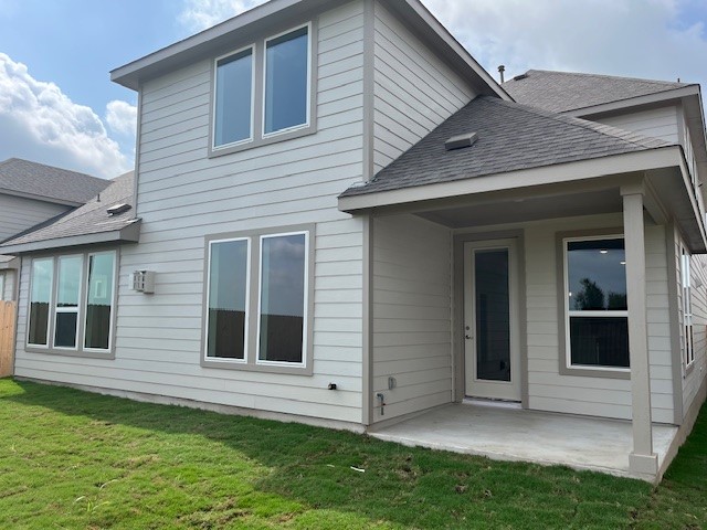 513 Teasley Dr, Taylor, TX 76574 - rear view of property featuring a shingled roof, a patio area, and a lawn