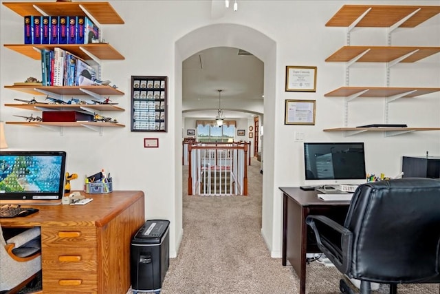 office area with arched walkways and light colored carpet