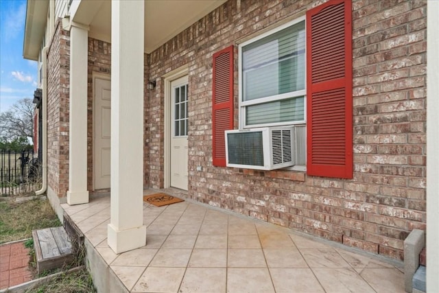 property entrance with fence, a porch, and brick siding