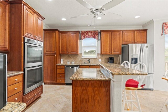 kitchen featuring stainless steel appliances, decorative backsplash, a sink, a kitchen island, and a kitchen breakfast bar