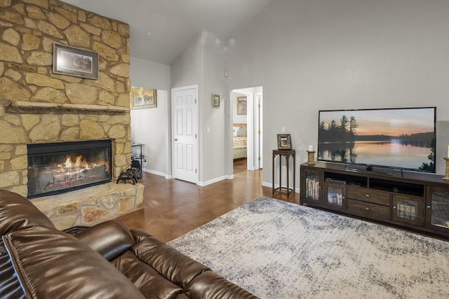 living room with finished concrete floors, a fireplace, high vaulted ceiling, and baseboards