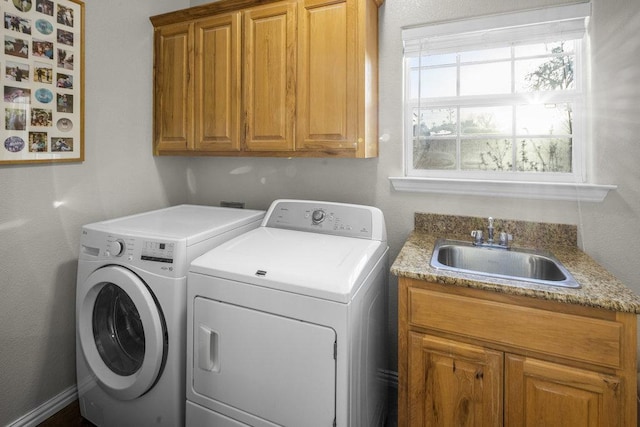 clothes washing area featuring cabinet space, separate washer and dryer, and a sink