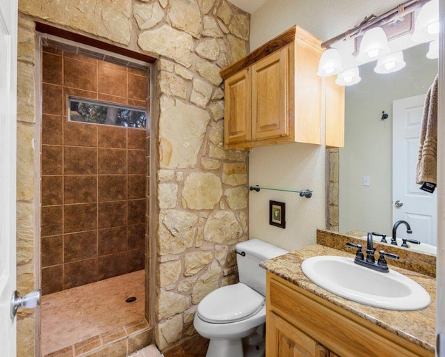 bathroom with tiled shower, toilet, and vanity