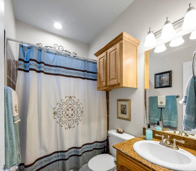 bathroom featuring a shower with shower curtain, toilet, vanity, and a textured wall