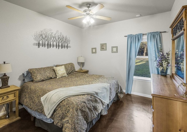 bedroom with multiple windows, a ceiling fan, concrete floors, and baseboards