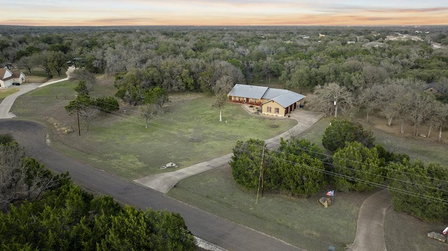 aerial view at dusk featuring a view of trees and a rural view