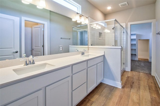 121 Pinnacle Ln, Kyle, TX 78640 - full bathroom with a shower stall, wood finished floors, double vanity, and baseboards
