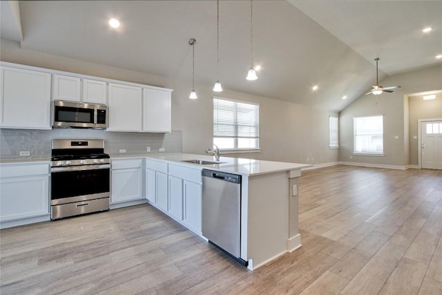 121 Pinnacle Ln, Kyle, TX 78640 - kitchen with appliances with stainless steel finishes, a sink, light countertops, light wood finished floors, and tasteful backsplash