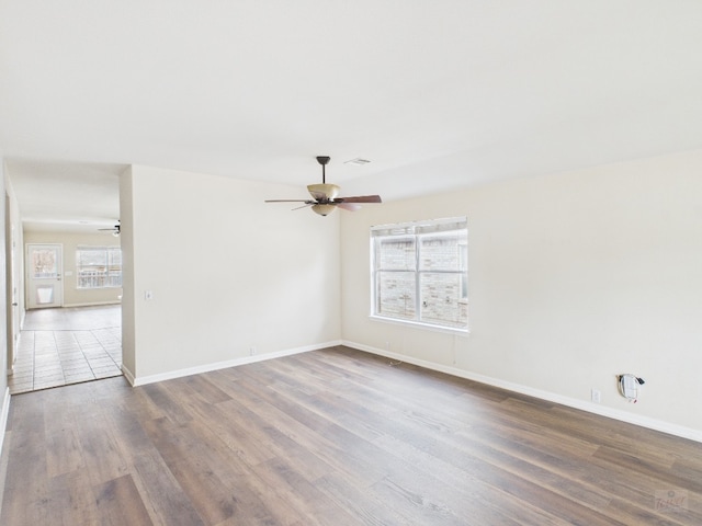 spare room featuring ceiling fan, visible vents, plenty of natural light, and wood finished floors