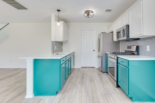 kitchen with blue cabinetry, appliances with stainless steel finishes, a sink, and visible vents