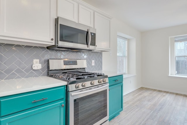 kitchen featuring baseboards, light countertops, appliances with stainless steel finishes, light wood-type flooring, and decorative backsplash