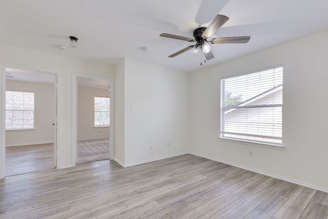 spare room with light wood-style floors, baseboards, and a ceiling fan