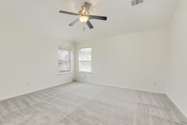 carpeted spare room with a ceiling fan, visible vents, and baseboards