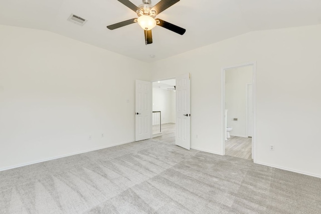 unfurnished room featuring light carpet, visible vents, vaulted ceiling, and a ceiling fan